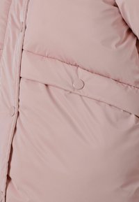 Vaateosa vaaleanpunaisesta topatuista takista, jossa on sileä pinta, nepparikiinnitykset ja vaakaompeleet eristystä varten. Yksinkertainen ja toiminnallinen muotoilu.