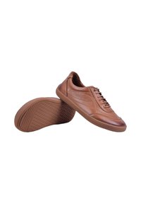 Baskets en cuir marron décontractées avec semelles en caoutchouc, une chaussure droite et l'autre inclinée pour afficher la semelle texturée.