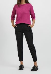 Fuchsia stickad tröja med rund hals, ihopparad med svarta smala byxor och svarta loafers med detaljer i guld.