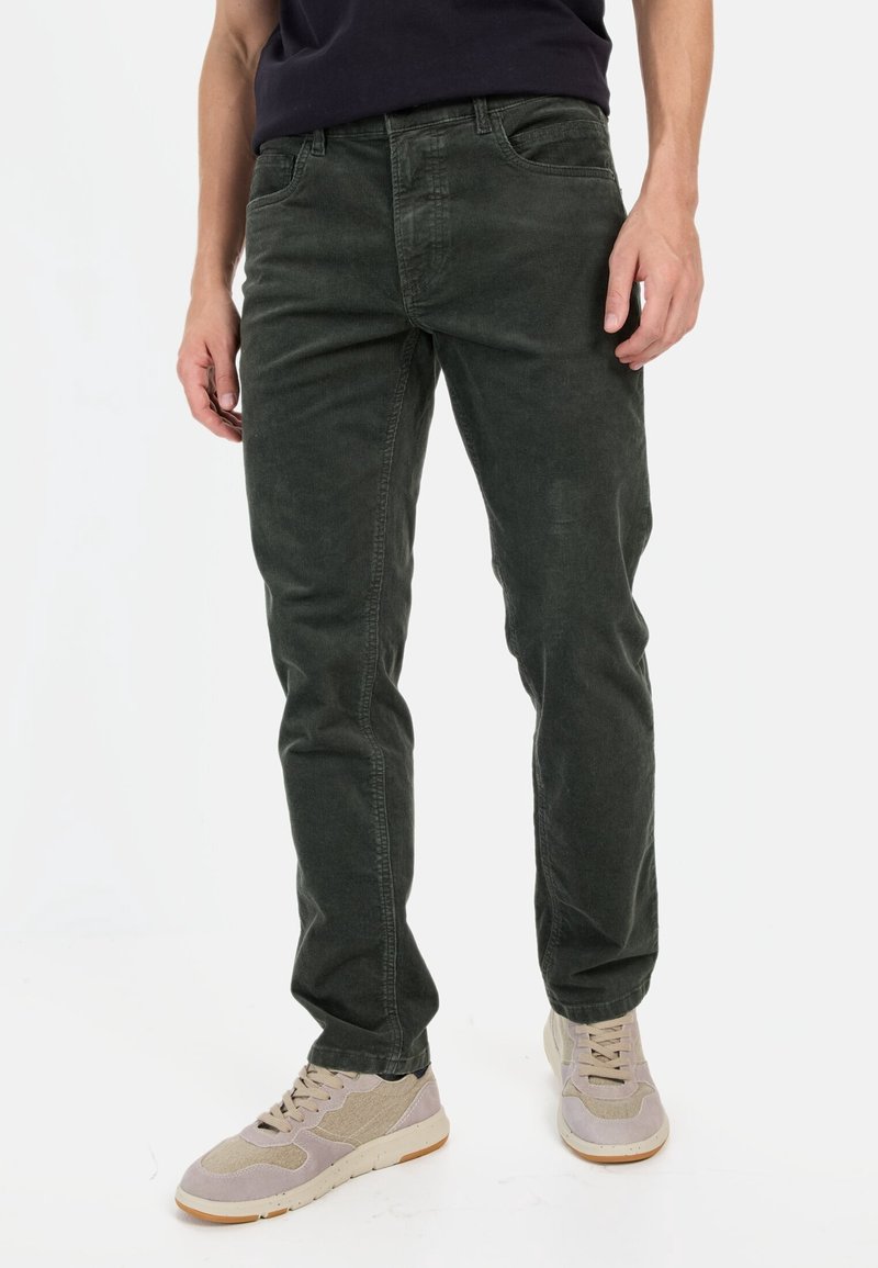 Donkergroene katoenen broek met een rechte pasvorm, voorzien van zakken aan de voorkant en een subtiele textuur. Gecombineerd met lichtgekleurde sneakers.