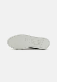 Kerek, fehér gumitalp textúrázott mintával és gravírozott "SELECTED / HOMME" márkázással; minimalista design, amely alkalmas a mindennapi viseletre.