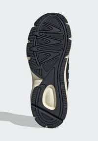 Semelle en caoutchouc noir avec un motif de bande de roulement en vagues et des sections texturées pour une meilleure adhérence. Semelle intermédiaire crème clair avec contour et détails en mousse.