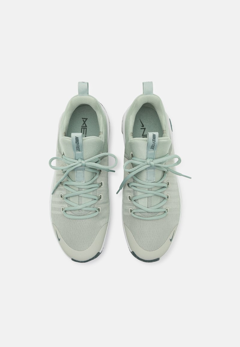 Zapatillas deportivas verde claro con upper de tela texturizada, puntera redonda y cordones planos. Presentan una tira de agarre y una suela blanca con acentos oscuros.