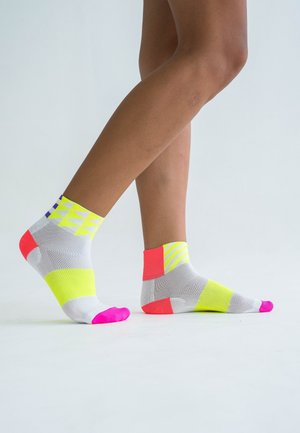 Knöchellange Socken in Grau mit neonfarbenen geometrischen Mustern in Gelb, Pink und Orange. Mit kontrastierenden Zehen- und Fersenbereichen. Leichtes Mesh-Material.