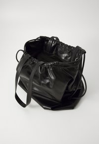 Borsa in pelle nera con chiusura a coulisse, texture morbida, base piatta e manici lunghi. Presenta un design minimalista senza hardware visibile.