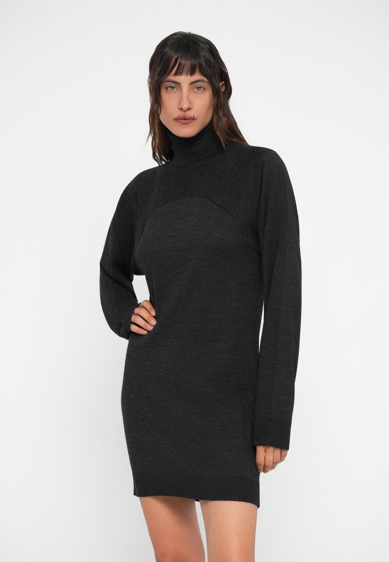 Sort, langærmet turtleneck kjole lavet af struktureret strikstof med tætsiddende liv og løse ærmer, der slutter over knæene.
