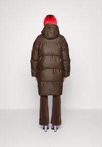 Brun puffet frakke med hætte, der har et quiltet design og et afslappet fit, parret med brune flare bukser og platform hæle.