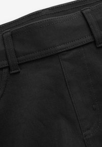 Juodi džinsai iš džinso audinio su struktūruotu liemeniu, matomomis siūlėmis ir šoninėmis kišenėmis. Audinys yra lygios tekstūros ir klasikinio silueto.