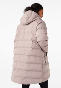Vadderad parka-jacka i mjuk beige, med huva, ribbade manschetter och sidofickor. Strukturerad, quiltad design med en avslappnad passform.
