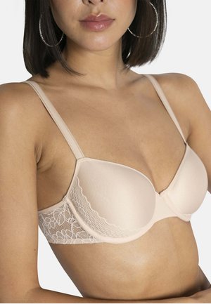 Soutien-gorge beige avec des bonnets rembourrés sans coutures, des bretelles réglables et des détails en dentelle sur les côtés, mettant en valeur une texture lisse et un design élégant.