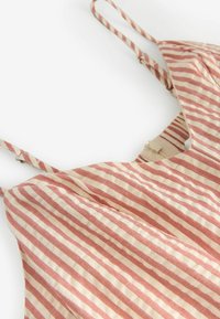 Robe rayée avec fines bretelles, présentant des rayures alternées rouges et crème, en tissu léger et au design décontracté.