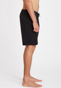 Shorts de bain noirs avec une taille à cordon, une poche latérale et un tissu lisse. Intérieur doublé et coupe mi-genou pour le confort.