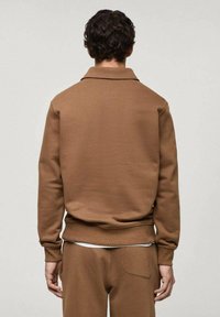 Brauner Sweatshirt mit Kragen, weicher Textur und elastischen Bündchen. Scheint über passender Unterbekleidung getragen zu werden. Einfaches, minimalistisches Design.
