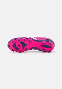 Suela de botines de fútbol Adidas en rosa brillante y púrpura con tacos angulares y rayas blancas en la parte superior, sobre un fondo blanco.