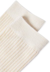 Calcetines de color beige claro con una textura suave y un puño liso. El canalé se extiende verticalmente a lo largo de la tela para añadir un detalle adicional.