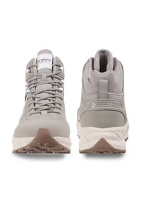 Jasnoszare buty trekkingowe z teksturowanej siateczki i materiałów syntetycznych, z masywną białą podeszwą środkową oraz gumową podeszwą z bieżnikiem zapewniającym przyczepność.