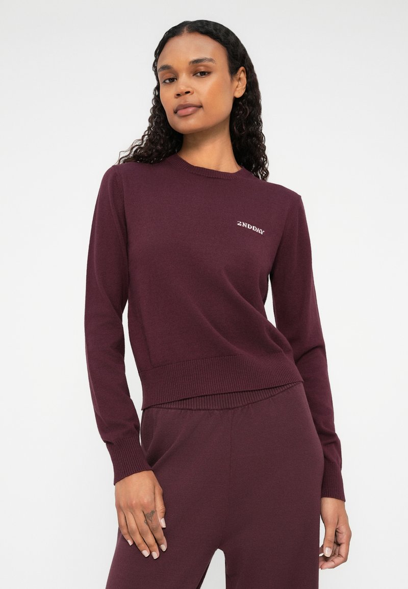 Bordeaux gebreide trui met ronde hals, geribbelde manchetten en zoom. "2NDDAY" logo geborduurd op de linkerkant van de borst. Een gladde textuur.