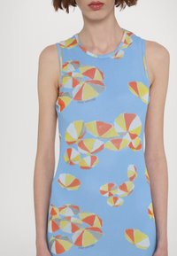 Top sans manches bleu avec un motif de ballons de plage colorés en jaune, orange, blanc et gris. Tissu lisse et extensible.