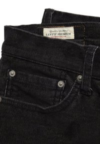 Svarta denimjeans med ribbad textur, silverfärgad metalldetalj och en märkesetikett som säger "Levi's Premium."