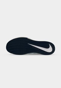 Μαύρη σόλα παπουτσιού με λευκό λογότυπο Nike swoosh και μοτίβο πέλματος σε σχέδιο ψαροκόκκαλου σε απλό λευκό φόντο.