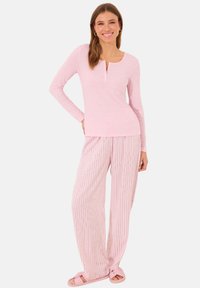 Light pink long-sleeve henley top with a button placket, paired with relaxed striped pants in matching shades, soft fabric and loose fit.