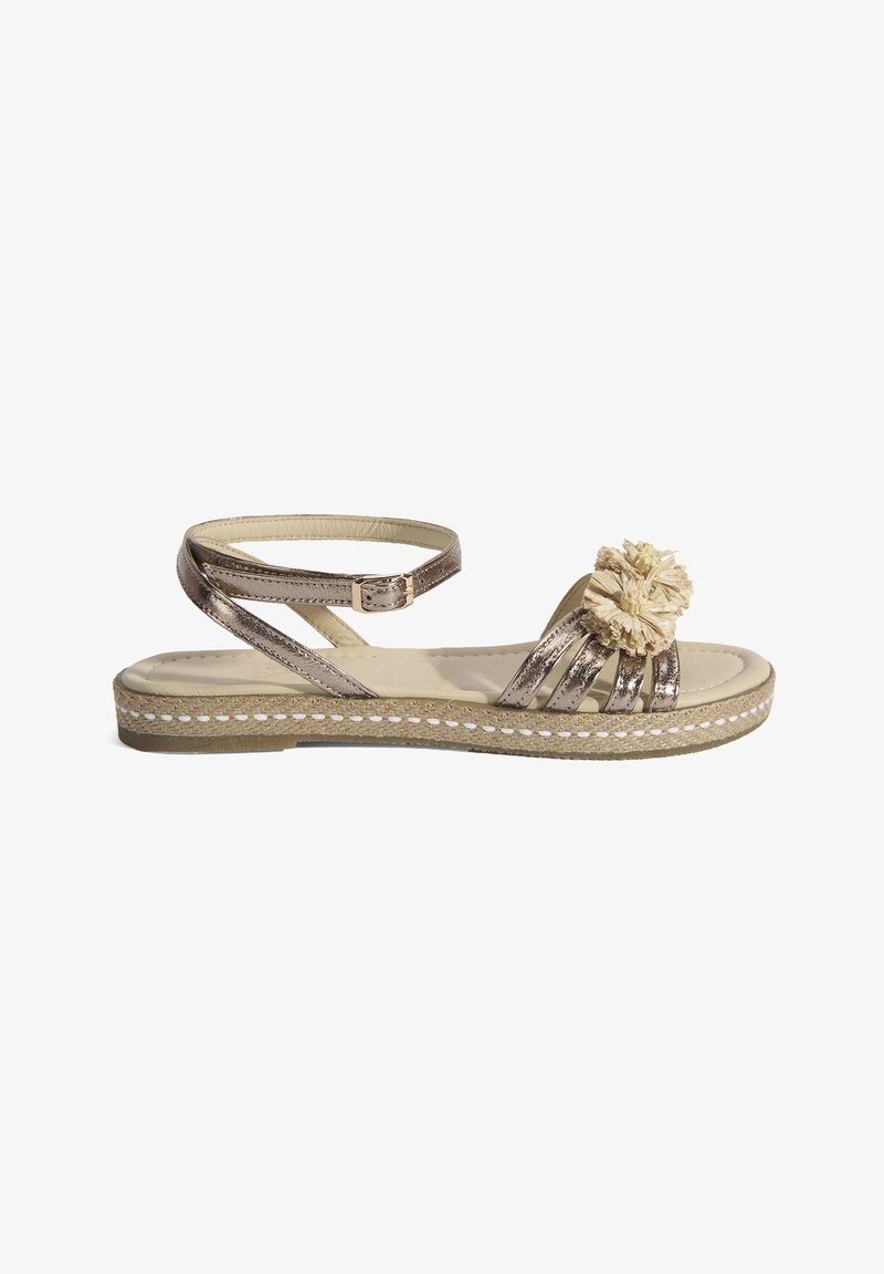 Metallisch bronze Sandale mit einem gewebten Riemendesign, ausgestattet mit einem dekorativen beigen Pom-Pom und einer strukturierten Espadrille-Sohle.