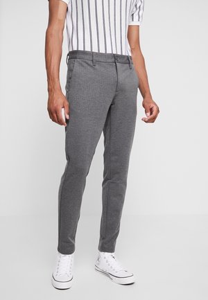 Pantalons gris slim-fit avec une finition texturée, dotés d'une fermeture à un bouton et de poches, associés à des baskets montantes blanches.