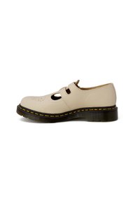 Scarpa in pelle beige con punta rotonda, design con ritagli e due aperture per cinturini. Cuciture gialle su una suola nera spessa aggiungono contrasto.