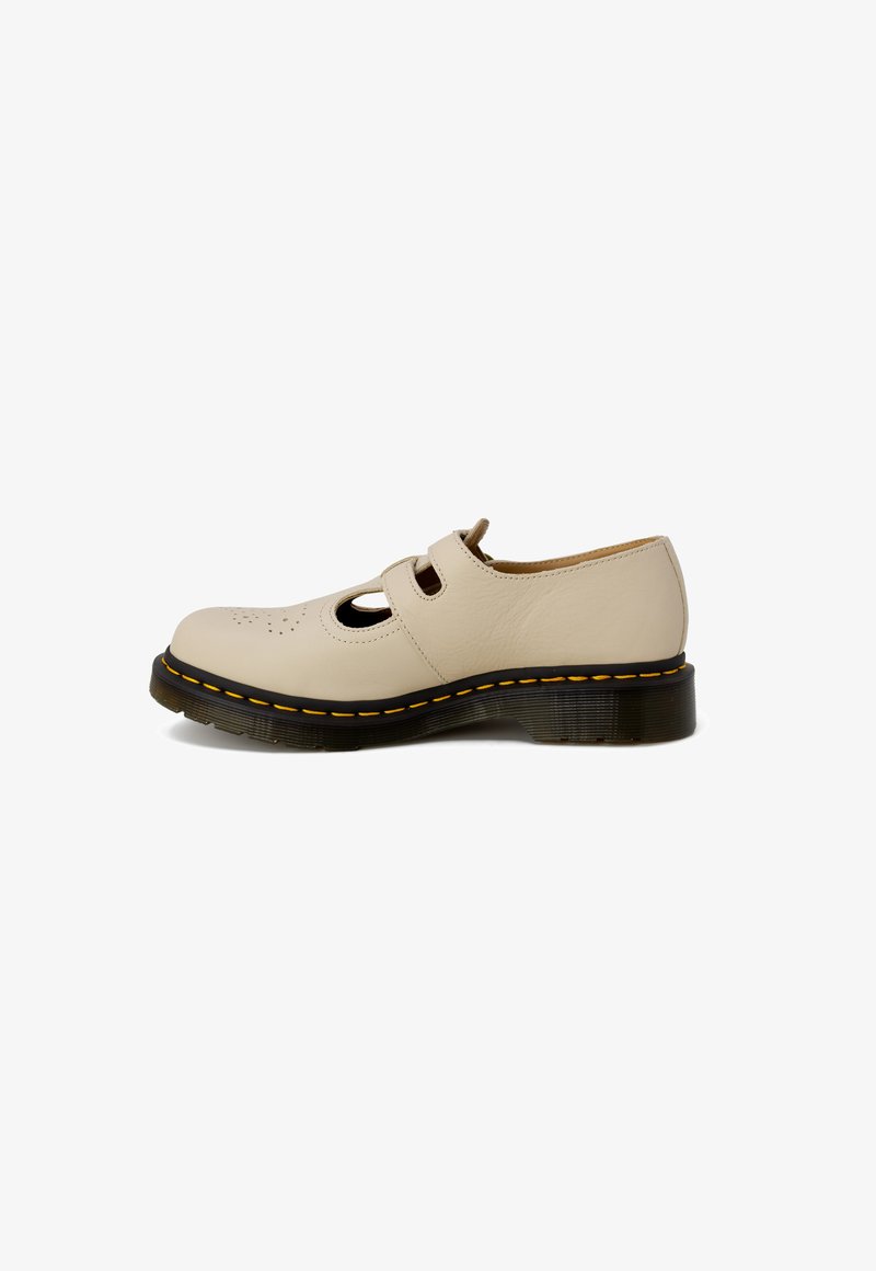 Chaussure en cuir beige avec un bout rond, un design à découpes et deux ouvertures avec des sangles. Des coutures jaunes sur une épaisse semelle noire ajoutent du contraste.