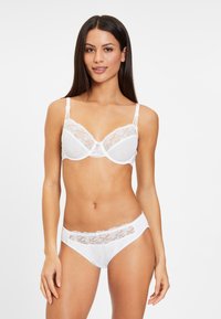 Witte lingerie set met kanten accenten. De beha heeft gevulde cups en verstelbare bandjes, terwijl de slip een kanten detail heeft bij de tailleband.