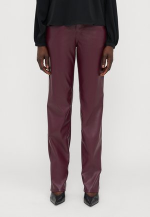 Pantaloni in ecopelle bordeaux con texture liscia, design a gamba dritta e tasche anteriori, abbinati a scarpe nere con punta affusolata.