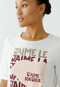 Weißes Baumwoll-T-Shirt mit mehrfarbigem Text und Herzgrafik. Der Text enthält Phrasen in verschiedenen Schriftarten, mit einem nassen Look auf den Herzdetails.