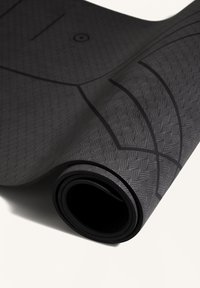 Černá podložka na jógu s texturovaným povrchem, zdobená vzorovaným designem a srolovaným okrajem, vyrobená z gumovitého materiálu.