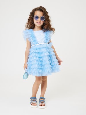 Abito a maniche corte blu chiaro con balze, corpetto bianco e gonna in tulle a strati. Abbinato a occhiali da sole blu rotondi e sandali.