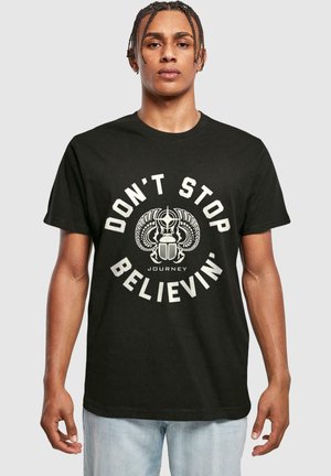 Sort bomulds T-shirt med et centralt grafik og hvid tekst "DON'T STOP BELIEVIN'" samt et design af vinger og en bille.