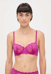 Lace bra in vibrant fuchsia with sheer cups, scalloped edges, and thin adjustable straps. Features floral pattern and hook closure.