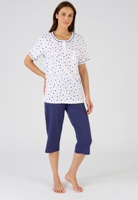 Conjunto de pijama de algodón ligero que incluye una parte superior blanca con patrones de corazones en rosa y azul, mangas cortas y pantalones capri azul marino.