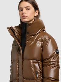 Brun vadderad jacka med glansig yta, hög krage, svart dragkedja och sidoficka. Har märkning på ärmen.