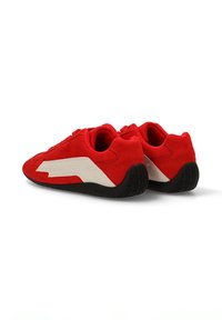 Zapatillas de ante rojo con un diseño en zigzag blanco, de perfil bajo, punta redonda y suela de goma negra. Adecuadas para uso casual o deportivo.