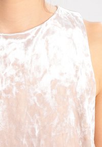 Tessuto di velluto rosa chiaro con una consistenza morbida, caratterizzato da un collo rotondo liscio e una leggera lucentezza, che mette in mostra modelli irregolari sulla superficie.