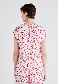 Abito a fiori con maniche corte a cappuccio, caratterizzato da un dettaglio sulla schiena a chiave. Tessuto leggero con sottili righe verticali in rosa e bianco.