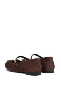 Brown suede flats with a rounded toe, features a bow accent and a small silver buckle on the strap. Low black rubber heel.