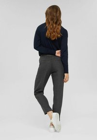 Pantalones de cuadros en blanco y negro con cintura elástica; combinados con una camiseta de manga larga azul marino y zapatillas blancas.