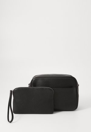 Deux sacs en cuir noir : un plus grand sac rectangulaire avec une fermeture éclair et une petite pochette avec une sangle pour le poignet, tous deux présentant une finition texturée.