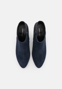Marineblaue Wildleder-Stiefeletten mit spitzer Zehe und Reißverschluss. Weicher Textur, elegantes Design mit einer glatten, minimalistischen Oberfläche. Logo ist innen sichtbar.