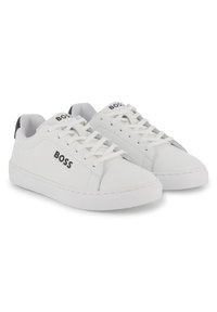 Λευκά δερμάτινα αθλητικά παπούτσια με υφασμάτινες λεπτομέρειες, επίπεδη ελαστική σόλα, στρογγυλή μύτη και λογότυπο στις πλευρές. Περιλαμβάνονται κορδόνια και επενδυμένος γιακάς.