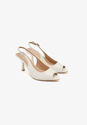 Chaussures à talons hauts slingbacks en cuir blanc avec bouts ouverts et brides réglables à la cheville, présentées côte à côte sur un fond blanc.