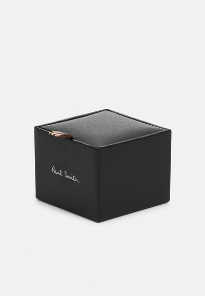 Svart firkantet eske med en teksturert overflate og topp, prydet med et fargerikt bånd og "Paul Smith"-signatur i hvitt på den ene siden.