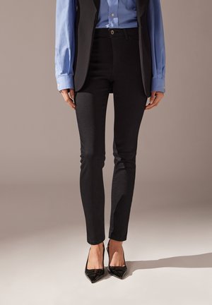 Svarta skinny jeans i denim, med en enkel design och en figursydd form, i kombination med klackskor i patentläder med spetsig tå.