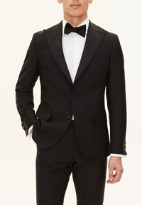 Svart tuxedo med satin krage, enkel knappstängning och vit, plisserad skjorta. Fluga fulländar den formella looken.
